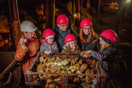 Grupa turystów z przewodnikiem w podziemiach Zabytkowej Kopalni Srebra ogląda fragmenty skał