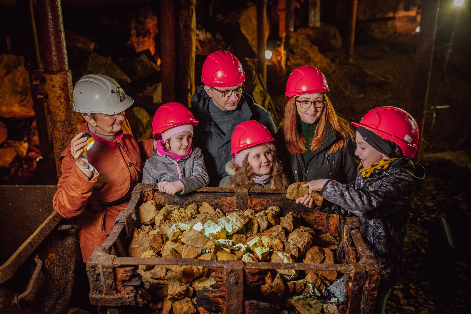 Grupa turystów z przewodnikiem w podziemiach Zabytkowej Kopalni Srebra ogląda fragmenty skał