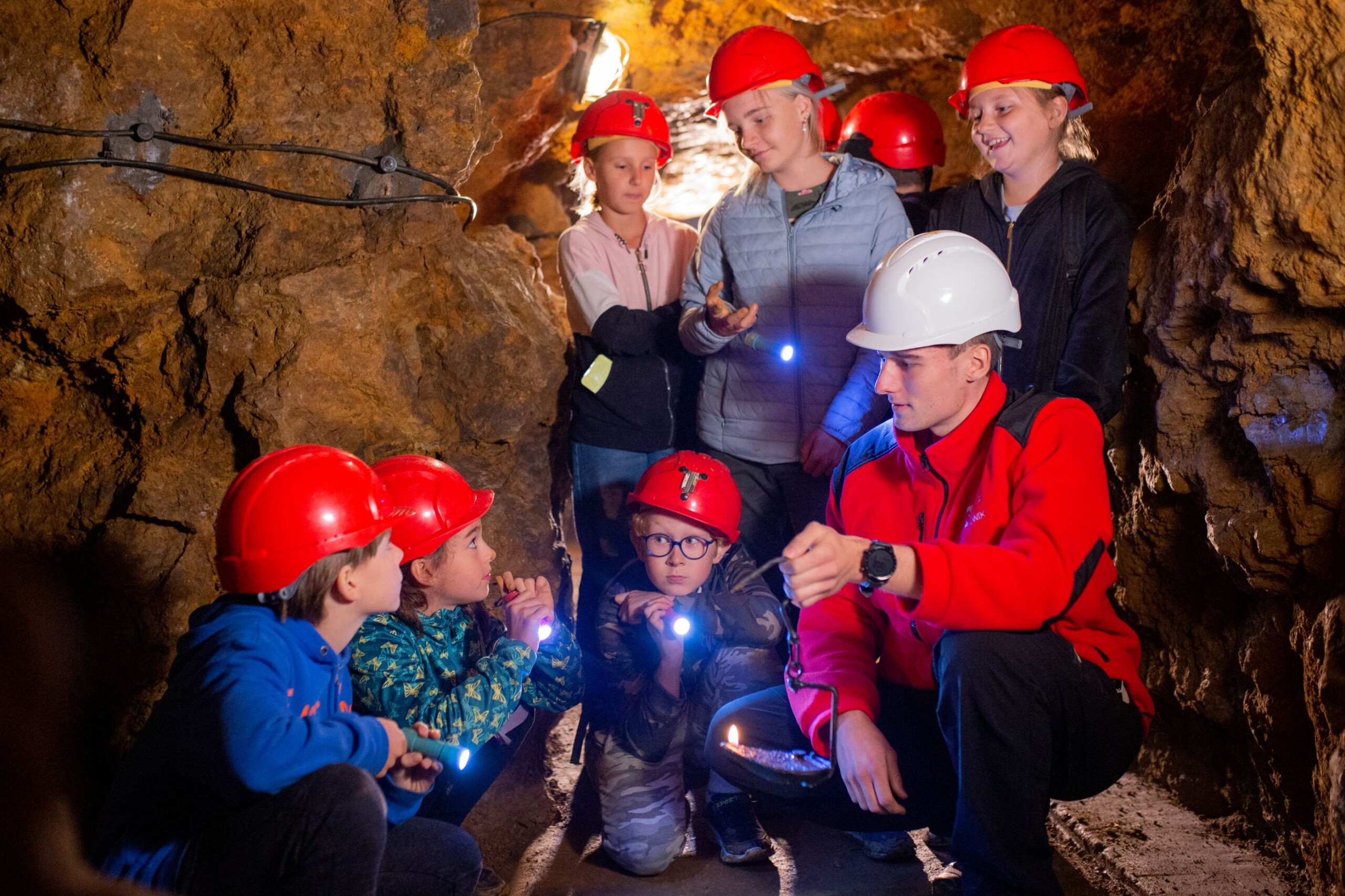 Grupa dzieci i przewodnik w podziemiach Zabytkowej Kopalni Srebra
